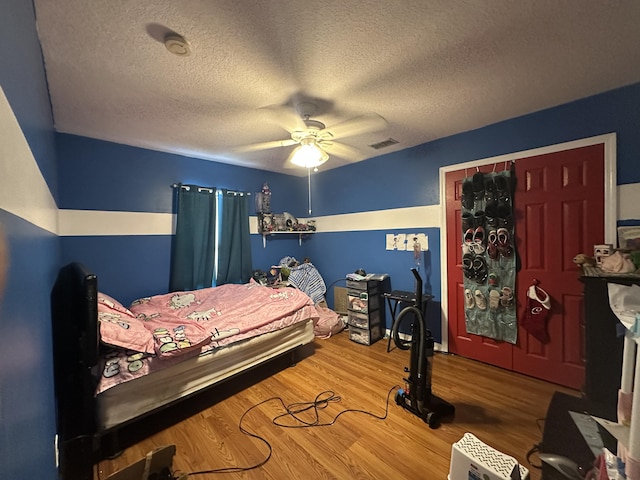 bedroom featuring visible vents, a textured ceiling, ceiling fan, and wood finished floors