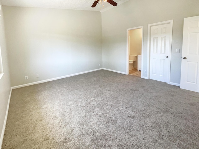 unfurnished bedroom featuring baseboards, lofted ceiling, carpet flooring, ensuite bathroom, and a ceiling fan