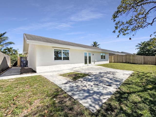 back of property featuring french doors, a yard, a fenced backyard, and stucco siding