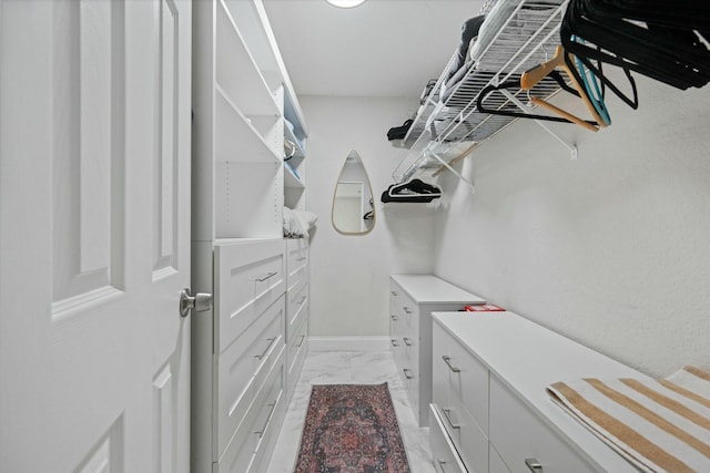 walk in closet featuring marble finish floor