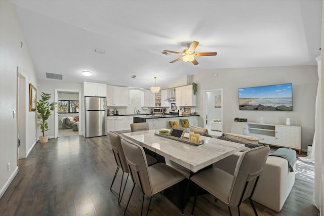 dining room featuring baseboards, visible vents, dark wood finished floors, ceiling fan, and vaulted ceiling