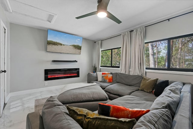 living area featuring baseboards, attic access, a glass covered fireplace, marble finish floor, and a ceiling fan