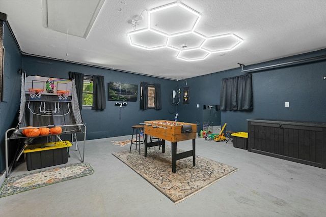 playroom featuring a textured ceiling, attic access, and finished concrete flooring