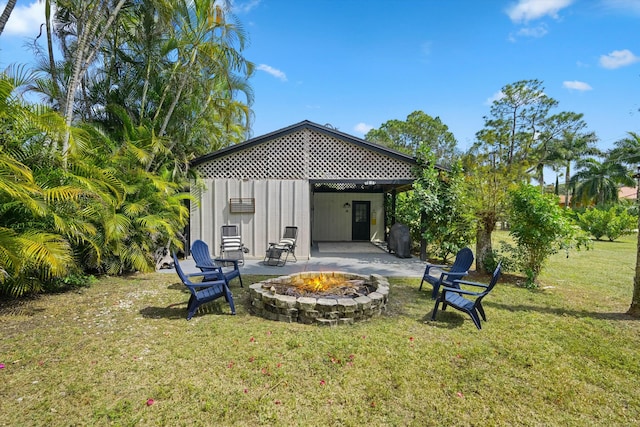 back of property with a patio area, a fire pit, and a yard