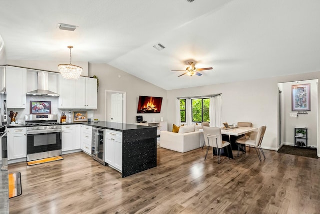 kitchen featuring visible vents, wine cooler, stainless steel gas range oven, wall chimney exhaust hood, and open floor plan