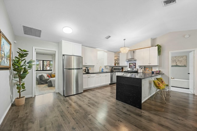 kitchen with dark countertops, wall chimney exhaust hood, visible vents, and stainless steel appliances