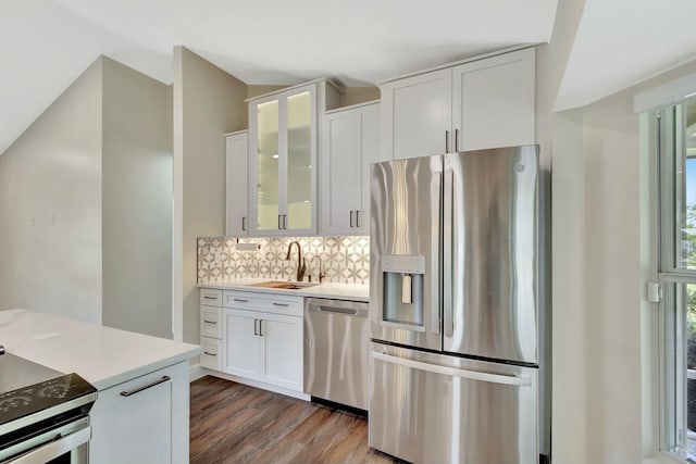 kitchen with light countertops, backsplash, appliances with stainless steel finishes, and a sink