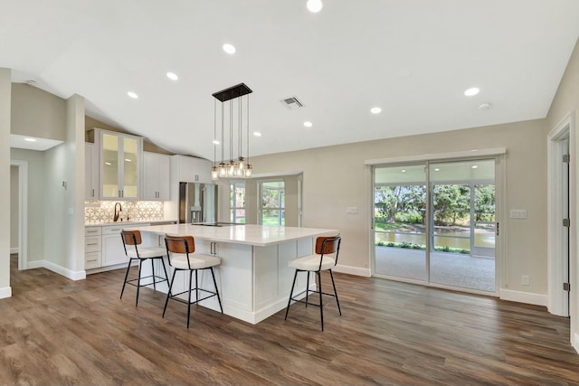 kitchen with tasteful backsplash, visible vents, lofted ceiling, stainless steel refrigerator with ice dispenser, and white cabinets