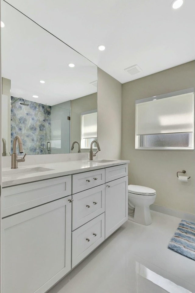 bathroom featuring double vanity, a shower stall, toilet, and a sink