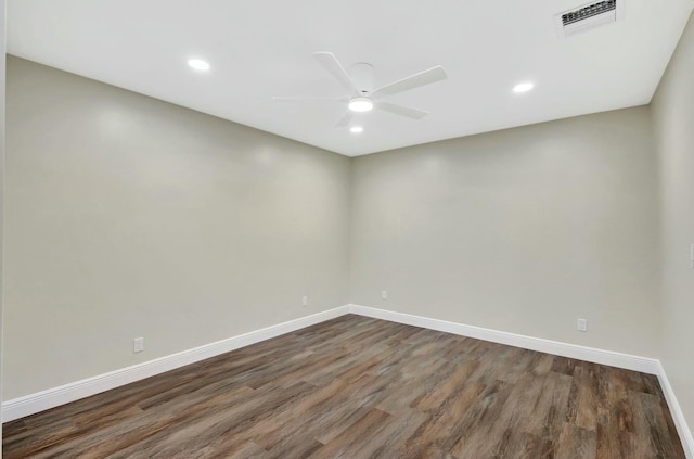 spare room with visible vents, a ceiling fan, dark wood-type flooring, and baseboards