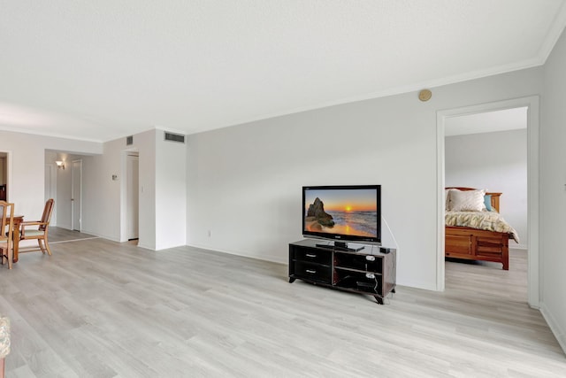 living area featuring visible vents, light wood-type flooring, baseboards, and ornamental molding