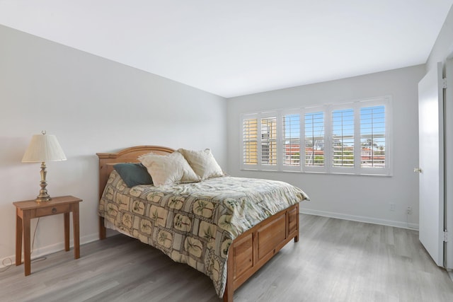 bedroom featuring light wood-style flooring, multiple windows, and baseboards