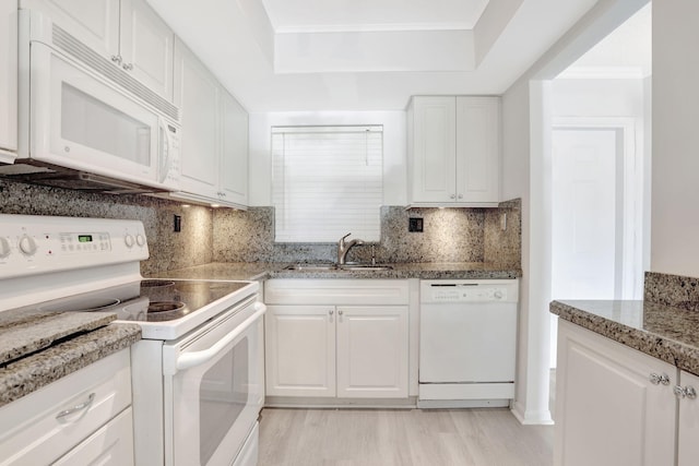 kitchen with white appliances, white cabinetry, and a sink