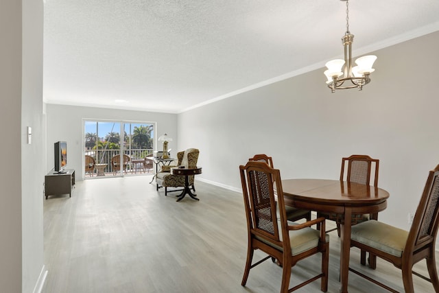 dining room featuring crown molding, baseboards, light wood-type flooring, a notable chandelier, and a textured ceiling