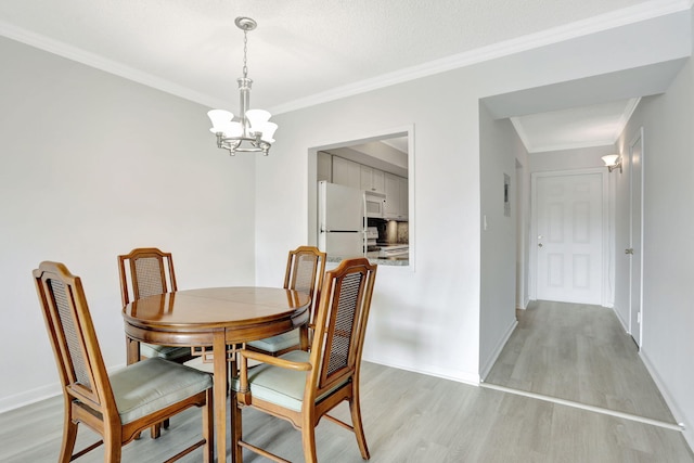 dining area featuring light wood-style flooring, a notable chandelier, baseboards, and ornamental molding