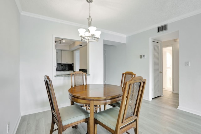 dining room with visible vents, light wood finished floors, and ornamental molding