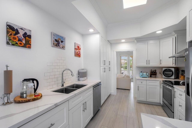 kitchen featuring ornamental molding, a sink, tasteful backsplash, stainless steel appliances, and light wood-style floors