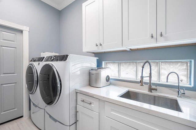 laundry room featuring washer and clothes dryer, a sink, cabinet space, light wood-style floors, and crown molding