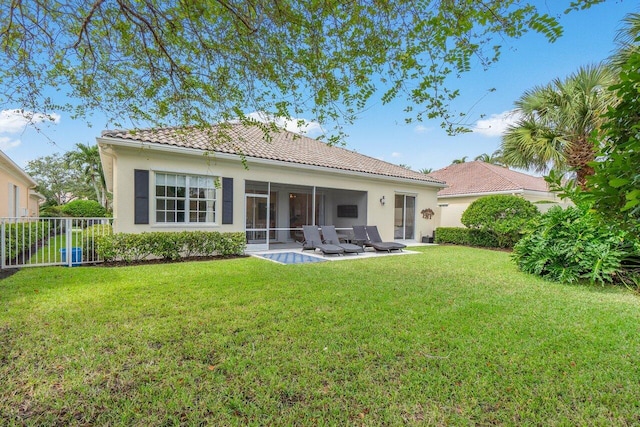 back of house featuring a patio, a sunroom, stucco siding, a tile roof, and a lawn