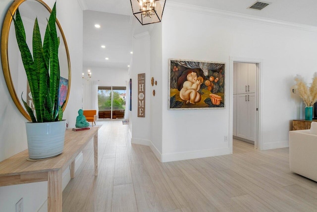 hallway featuring baseboards, visible vents, ornamental molding, a notable chandelier, and light wood-type flooring