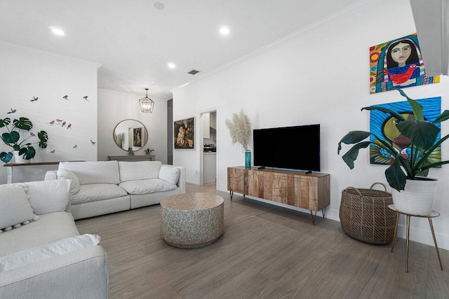 living room with visible vents, wood finished floors, and crown molding