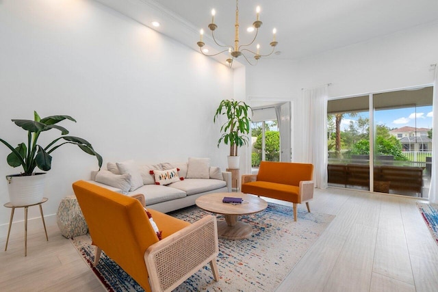 living area with a chandelier, ornamental molding, and light wood finished floors