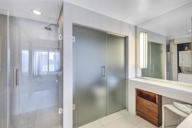 full bath featuring stacked washer and dryer, a stall shower, and tile patterned flooring