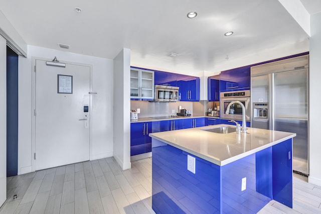 kitchen with light countertops, blue cabinets, appliances with stainless steel finishes, glass insert cabinets, and visible vents