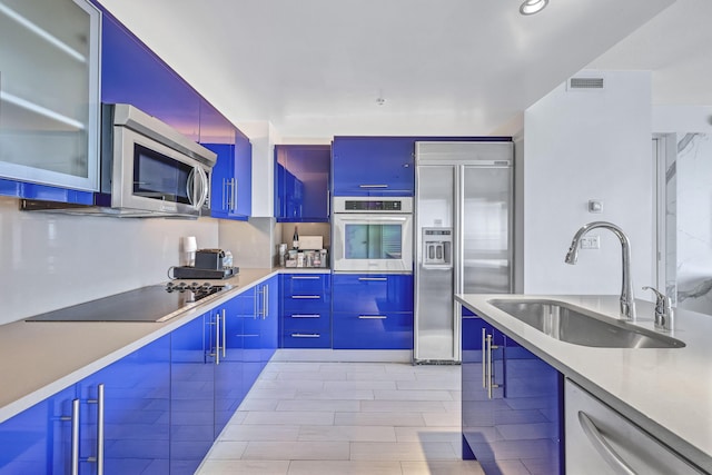 kitchen featuring a sink, visible vents, modern cabinets, appliances with stainless steel finishes, and glass insert cabinets