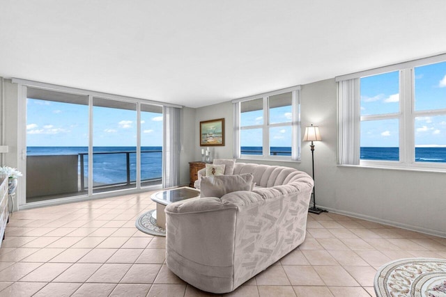 living area featuring light tile patterned flooring, a wall of windows, baseboards, and a water view