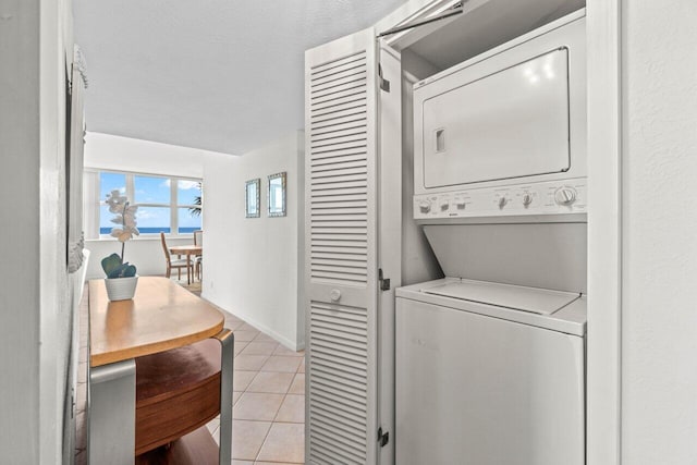 laundry room featuring light tile patterned floors, stacked washer and clothes dryer, and laundry area