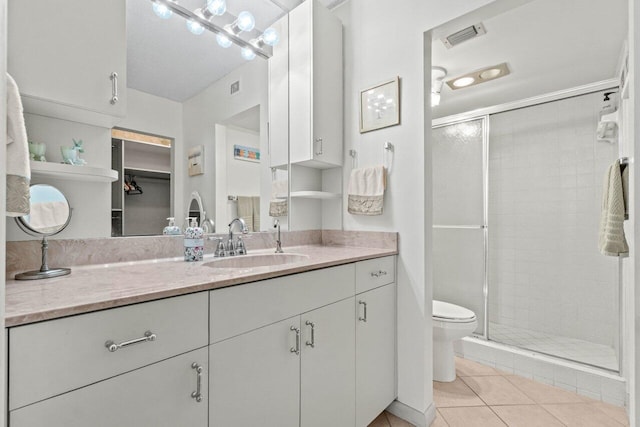 bathroom featuring tile patterned floors, a stall shower, toilet, and vanity