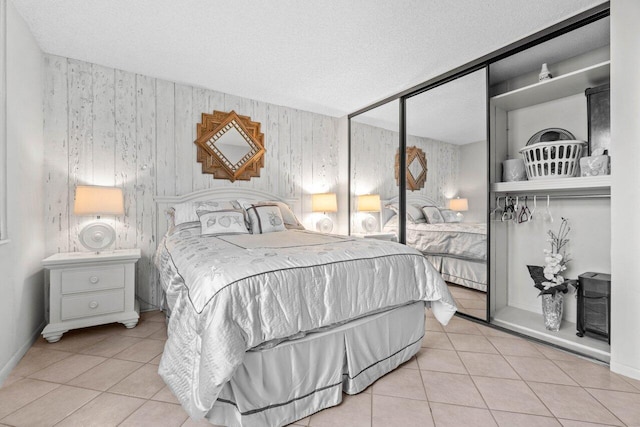 tiled bedroom featuring a closet, a textured ceiling, and baseboards