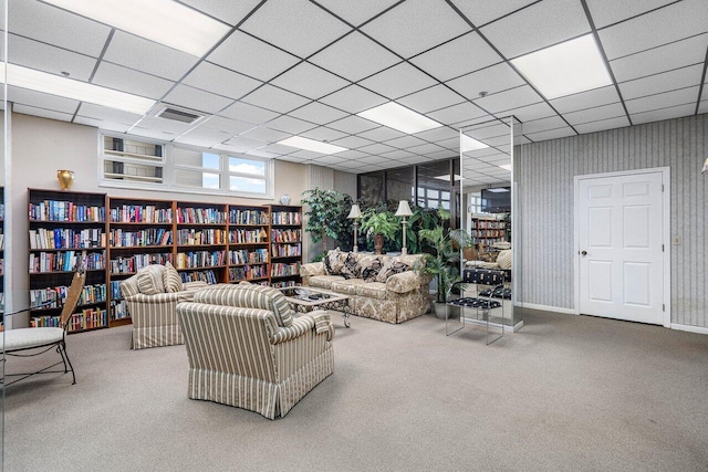 living room with a drop ceiling, visible vents, carpet flooring, and bookshelves