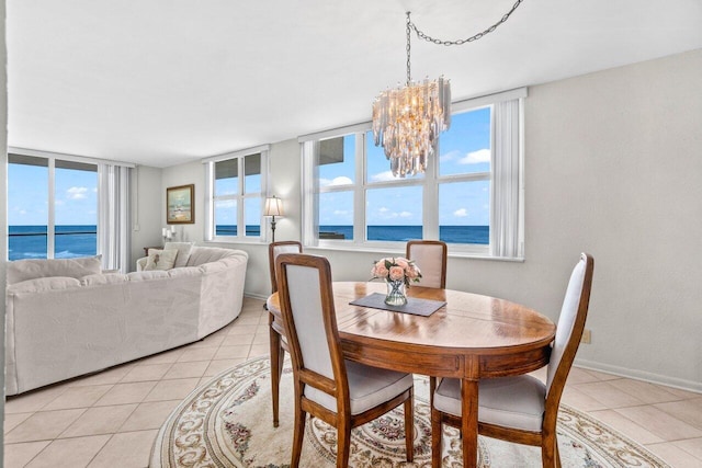 dining area featuring light tile patterned flooring, baseboards, plenty of natural light, and a water view