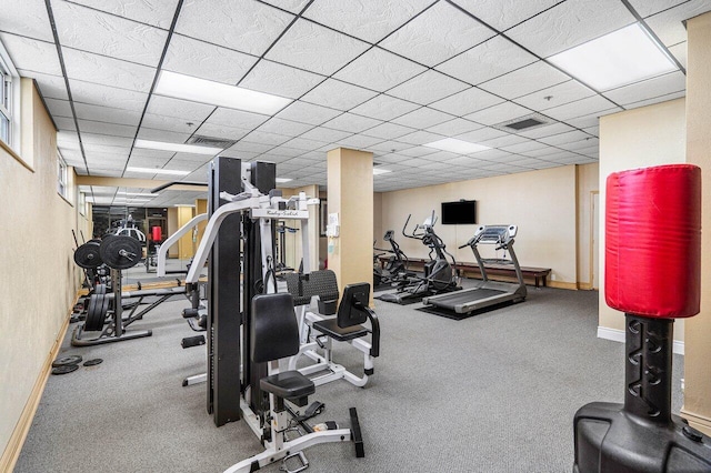 workout area featuring carpet, visible vents, a paneled ceiling, and baseboards