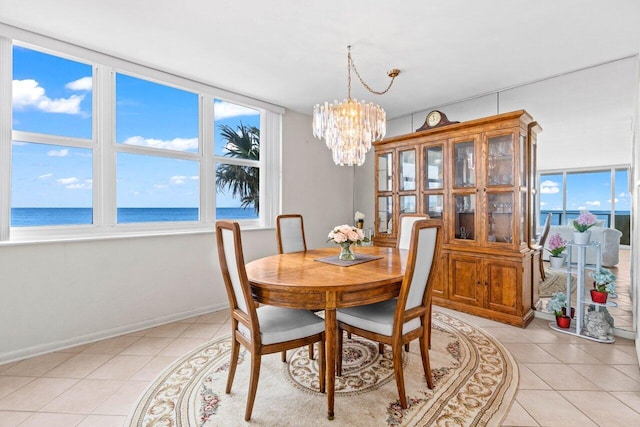 dining room with light tile patterned floors, baseboards, a water view, and an inviting chandelier