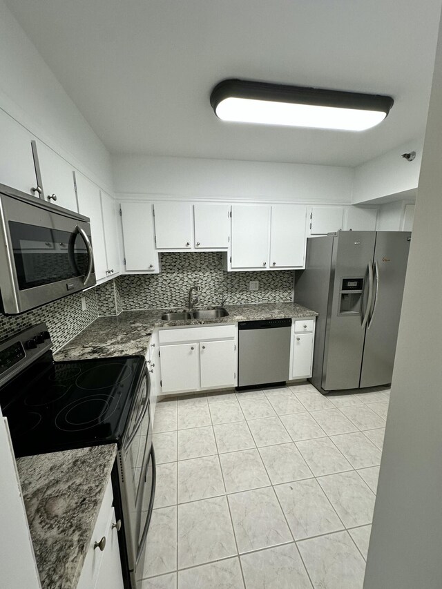 3850 Washington St Unit 510, Hollywood, FL 33021 - kitchen featuring white cabinets, light tile patterned flooring, a sink, stainless steel appliances, and decorative backsplash