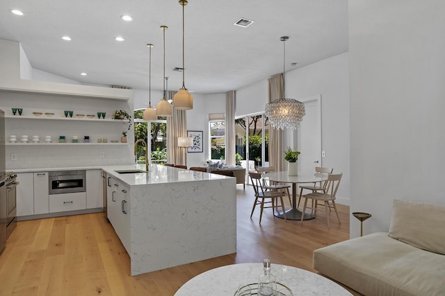 kitchen with visible vents, a sink, light wood-type flooring, hanging light fixtures, and open shelves