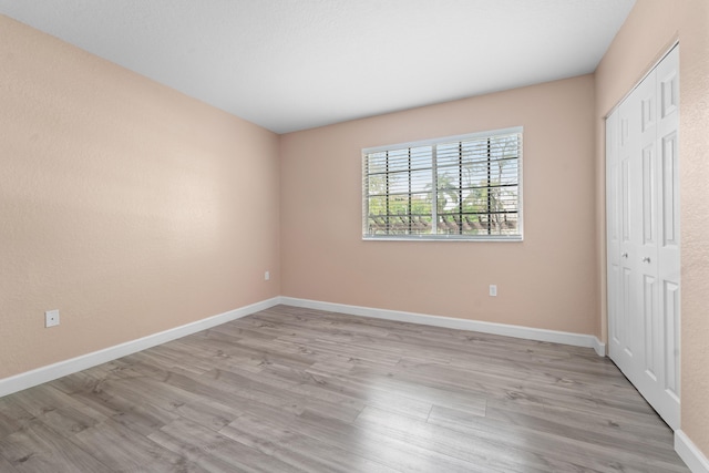 unfurnished bedroom with a closet, light wood-style flooring, and baseboards