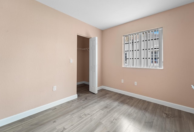 unfurnished bedroom featuring wood finished floors, baseboards, and a closet