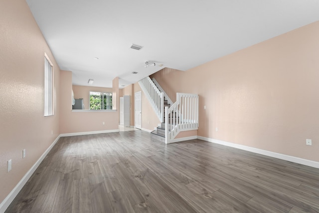 unfurnished living room featuring dark wood finished floors, visible vents, stairs, and baseboards