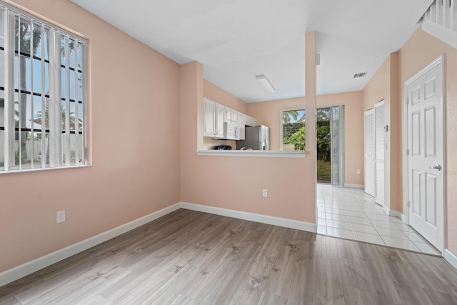 empty room featuring light wood finished floors, visible vents, and baseboards