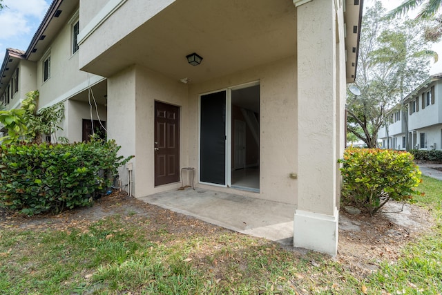 entrance to property with a patio and stucco siding