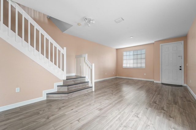 entrance foyer with stairway, baseboards, visible vents, and wood finished floors