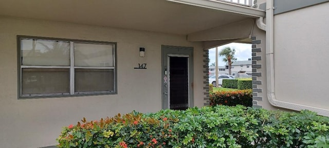 entrance to property with stucco siding and a balcony