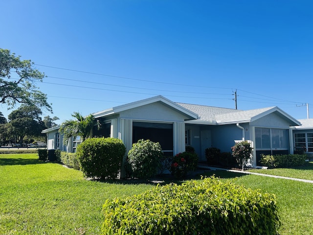 view of front of home with stucco siding, an attached garage, a front lawn, and roof with shingles