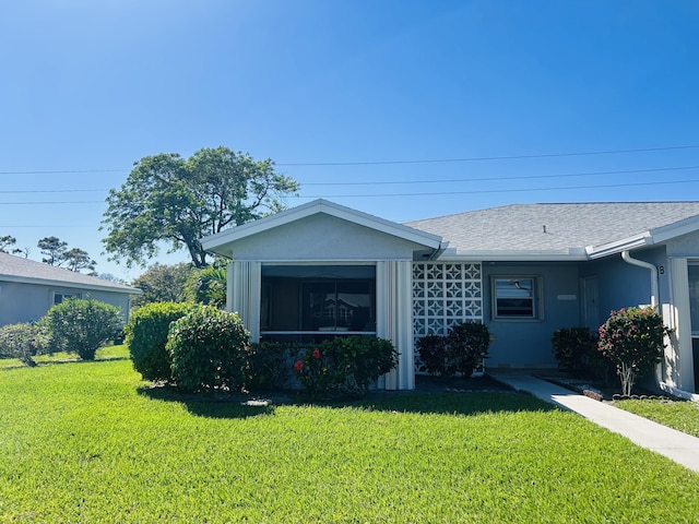 view of front of house featuring stucco siding, a front lawn, and a shingled roof