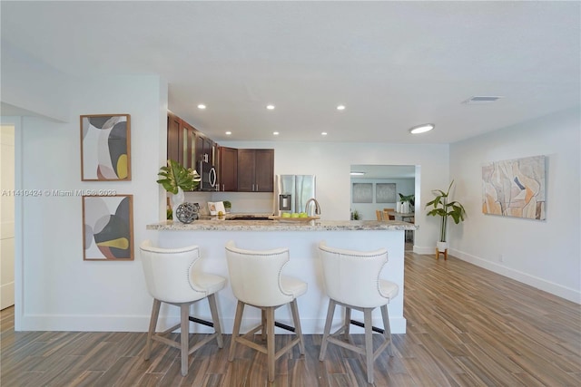 kitchen with visible vents, a kitchen breakfast bar, appliances with stainless steel finishes, and wood finished floors