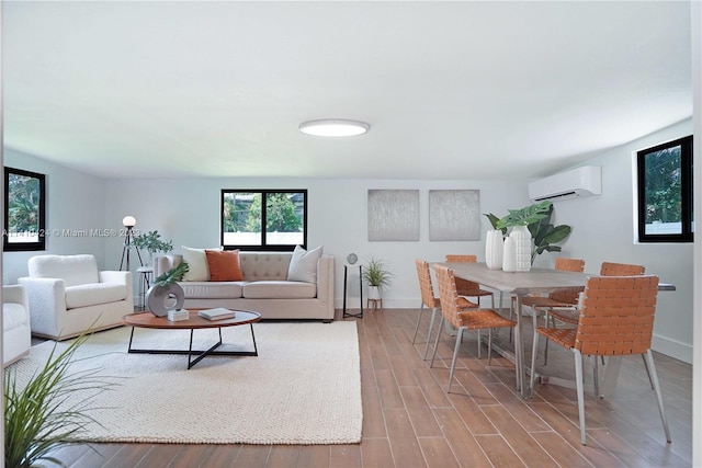 living room with a wall mounted air conditioner, baseboards, and wood finished floors